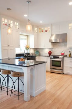 a large kitchen with white cabinets and black counter tops, an island in the middle is surrounded by stools