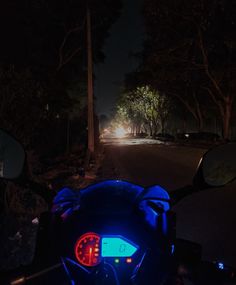 a motorcycle parked on the side of a road at night with its headlights turned on