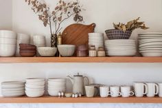 the shelves are filled with dishes, cups and vases on top of each other