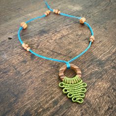 a green and blue necklace with wooden beads on a wood table next to a beaded bracelet