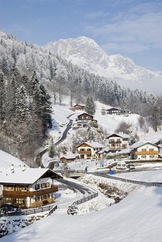 a snow covered mountain with houses on it's sides and mountains in the background