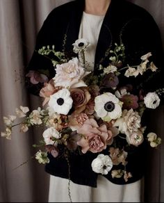 a woman holding a bouquet of flowers in front of her face and wearing a black jacket