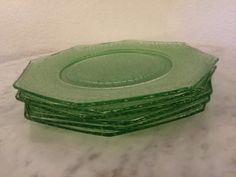 a stack of green glass plates sitting on top of a white tablecloth covered floor