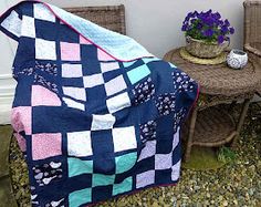 a blue and pink blanket sitting on top of a table next to a wicker chair