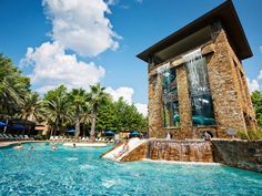 an outdoor swimming pool surrounded by trees and umbrellas