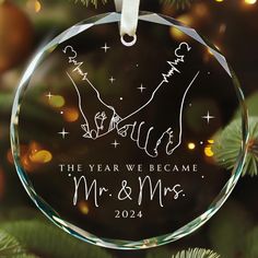 a glass ornament with the year we came mr and mrs on it hanging from a christmas tree