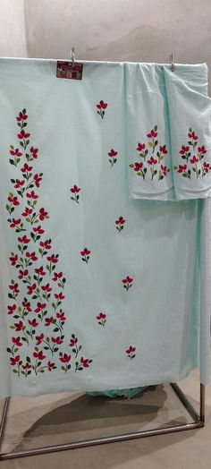 two towels hanging on a towel rack with red flowers and green leaves painted on them