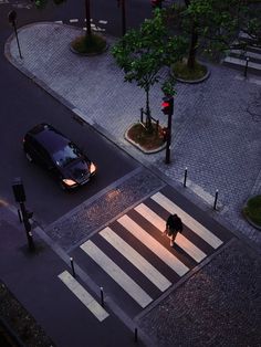 an overhead view of a person walking across a crosswalk in the city at night