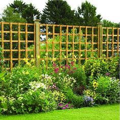 a garden filled with lots of different types of flowers and plants next to a wooden trellis