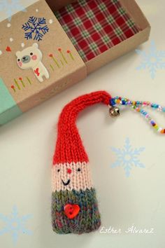 a knitted santa clause ornament next to a box with a christmas decoration on it