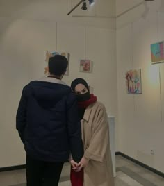 two people standing next to each other in an art gallery