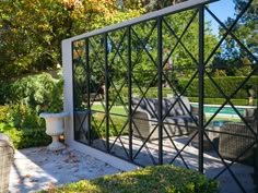 an outdoor patio with chairs and tables next to a swimming pool in the middle of a garden