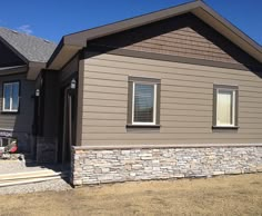 a house that is in the middle of some dirt and grass with two windows on each side