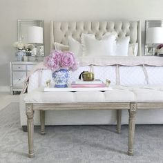 a white couch sitting in front of a mirror on top of a dresser next to a bed