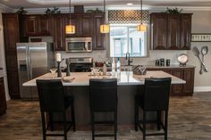 a large kitchen with an island in the middle and two chairs at the counter top