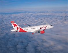 an airplane is flying above the clouds in the day time, it appears to be red and white