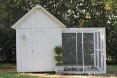 a white chicken coop with a potted plant in it