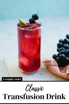 a close up of a drink in a glass on a table with grapes and lime