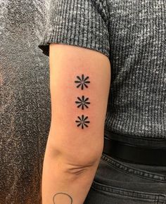 a person with a tattoo on their arm that has four small flowers in the middle