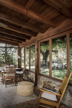 a screened porch with chairs and tables on the floor, surrounded by wood paneling