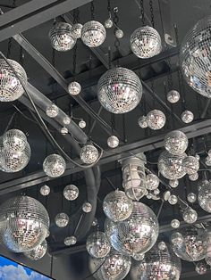 many disco balls hanging from the ceiling in front of a blue sky and white clouds