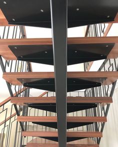 a spiral staircase with wooden treads and metal handrails is seen in this image