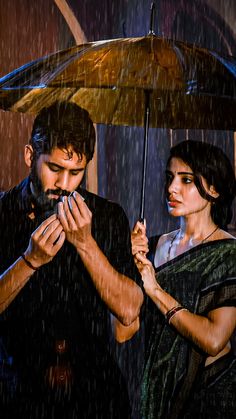 a man and woman standing under an umbrella in the rain with their hands on each other