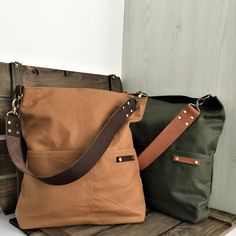 two purses sitting on top of a wooden bench next to each other, one brown and one green