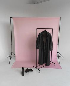 a pink backdrop with a coat and shoes on it