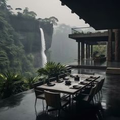 an outdoor dining area with a waterfall in the back ground and table set for four