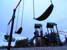 an empty playground with swings and slides in the evening time, on a cloudy day