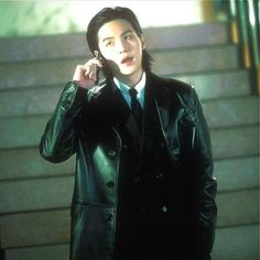 a man in a suit and tie talking on a cell phone while standing next to stairs