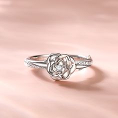 Around the world, the rose is one of the most universal flowers used to express love. This romantic ring poetically evokes a tender promise of love. The rose-inspired stylised bud delicately unfurls its petals, creating the illusion of a real flower. The centre stone sparkles as though bathed in dew.Carat Weight: 0.305 ctStone Size: 1,2 mmStone Type: Jeulia® StoneNumber of Stones: 25 Stone Color: Diamond WhiteStone Shape: RoundWeight: 3 gWidth: 1.9 mmHeight: 5.6 mmThickness: 1.4 mmMaterial: 925 Rose Gold Flower Ring For Promise, Rose Gold Flower Promise Ring, Elegant Rose-colored Flower Ring As Gift, Elegant Rose Flower Ring As Gift, Elegant Rose-colored Flower Ring For Gift, Elegant Rose Colored Flower Ring As Gift, Elegant Rose Flower Ring For Gift, Elegant Flower Shaped Promise Ring, Elegant Rose Gold Flower Ring With Roses