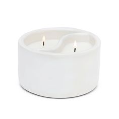 two white candles sitting inside of a bowl