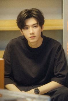 a young man sitting in front of a book shelf