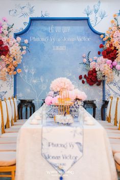 a table with flowers and candles on it in front of a blue sign that says welcome to us