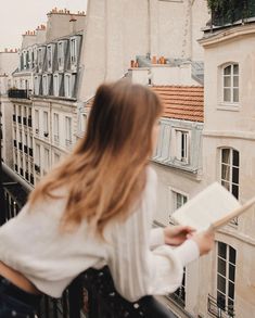 a woman standing on a balcony reading a book