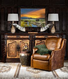 a brown chair sitting in front of a painting on top of a wooden dresser next to two lamps