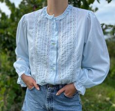 "Romantic light blue cotton-blend puff sleeve blouse. Delicate lace trim at neckline, sleeve opening and either side of pintuck detail. Balloon sleeves with elasticated opening and ruffle. Button-up closure. Made in the USA. Size S/M  Bust (1\" below armhole): 47\" Front Length (high point shoulder to hem): 26\" Machine wash cold. Hang dry. 65% Polyester 35% Cotton" Blue Lace Blouse, Pintuck Blouse, Soft Gamine, Light Blue Shirts, Puff Sleeve Blouse, Blue Vintage, Pin Tucks, High Point, Balloon Sleeves