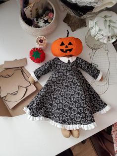 a doll is sitting on a table with paper and other crafting supplies around it