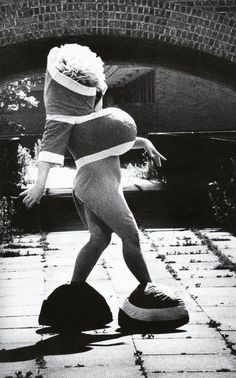 a woman in a bathing suit is balancing on a round object near a brick wall