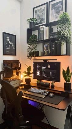 a desk with a computer, keyboard and plant on it in front of two framed pictures