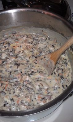 a pot filled with food sitting on top of a stove next to a wooden spoon