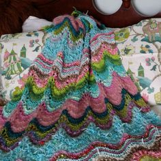 a crocheted blanket laying on top of a bed next to an egg holder