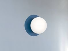 a white ball hanging from the side of a gray wall with a blue circle around it