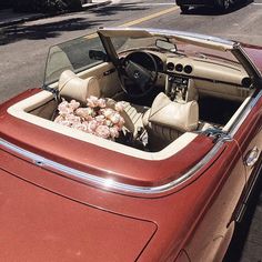 the interior of an old convertible car with flowers on the dash board and center console