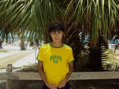 a young man standing in front of a palm tree