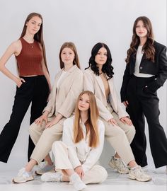 four women are posing for the camera in front of a white background