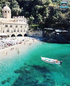 people are swimming in the clear blue water near a beach with a boat on it