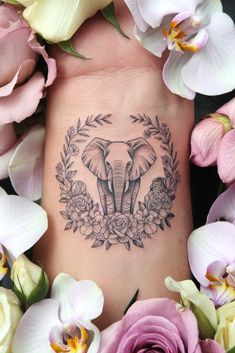 an elephant tattoo on the ankle with flowers around it